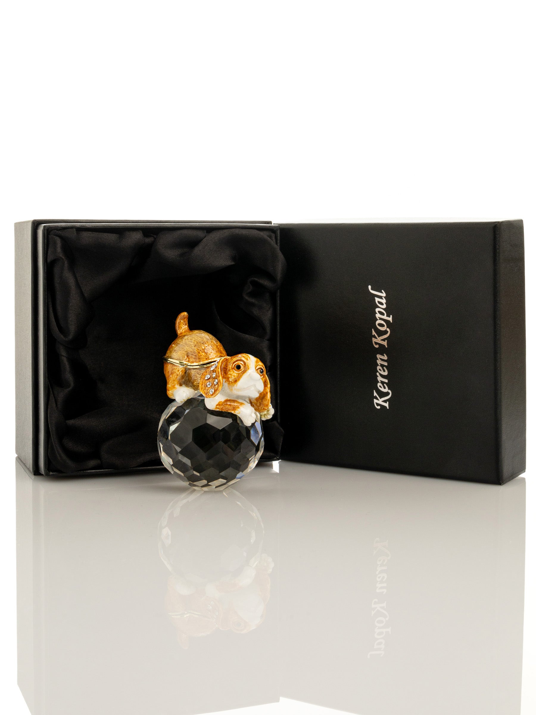 Dog figurine on a crystal ball with a black box branded 'Keren Kopal' in the background.