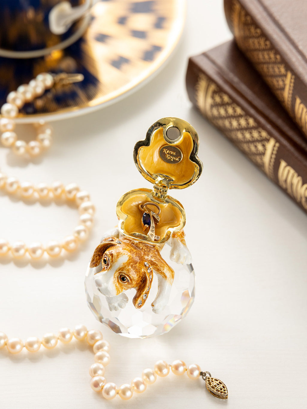 Gold and crystal pendant with pearl necklace on a white surface