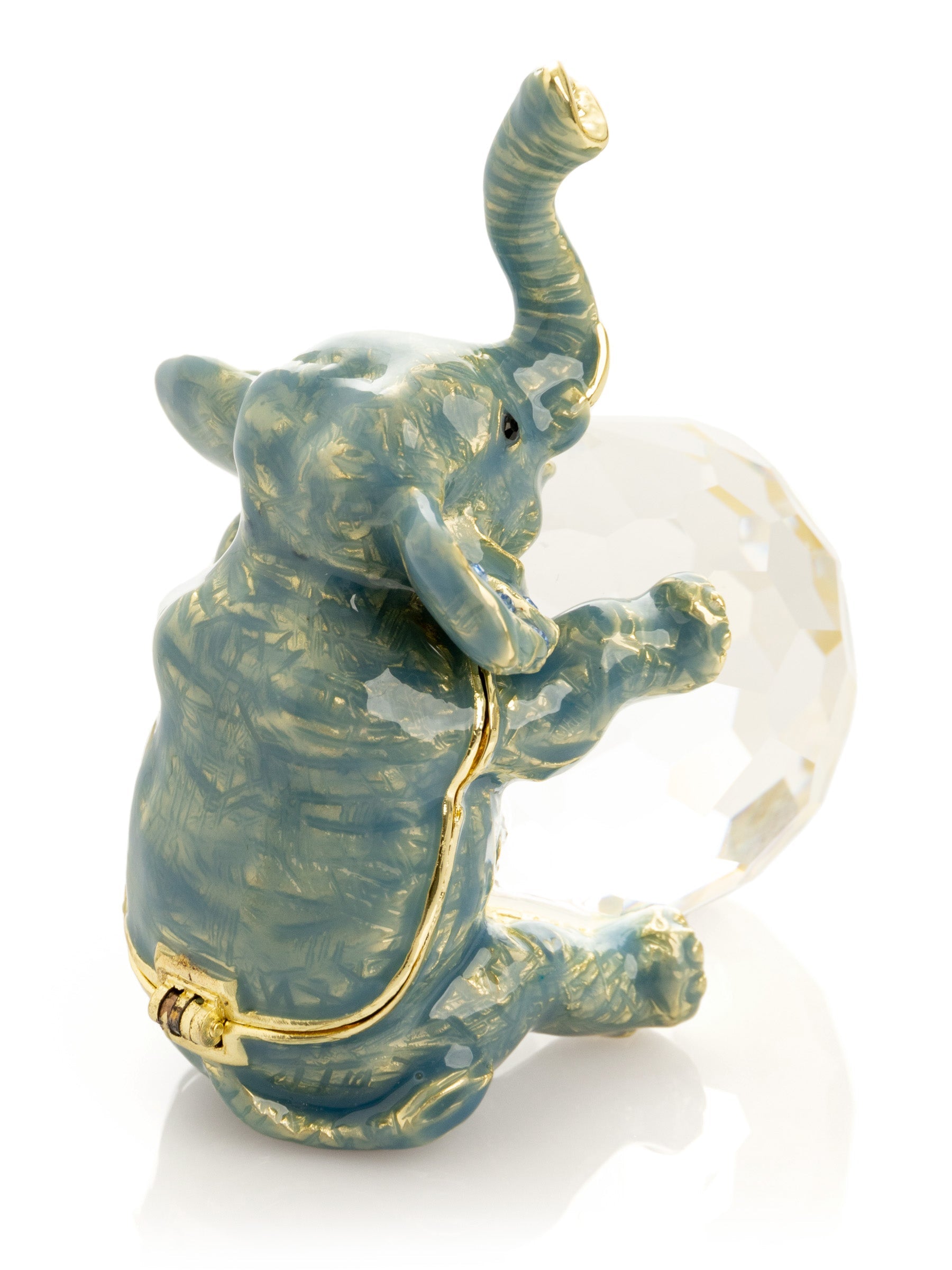Decorative elephant figurine with a gold trunk and base, holding a crystal ball on a white background