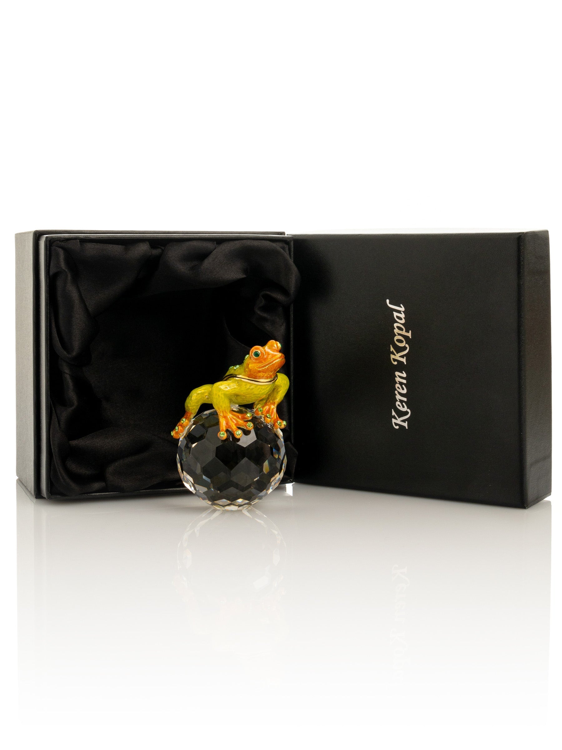 Frog figurine on a crystal ball in front of a branded box
