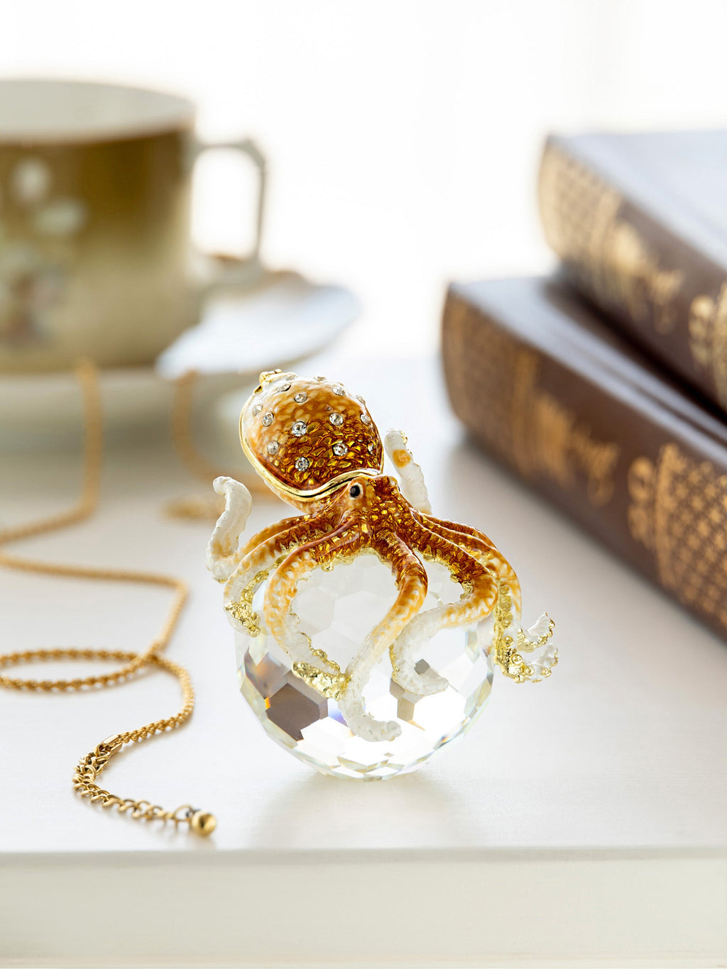 Crystal octopus necklace on a table with a cup and book in the background