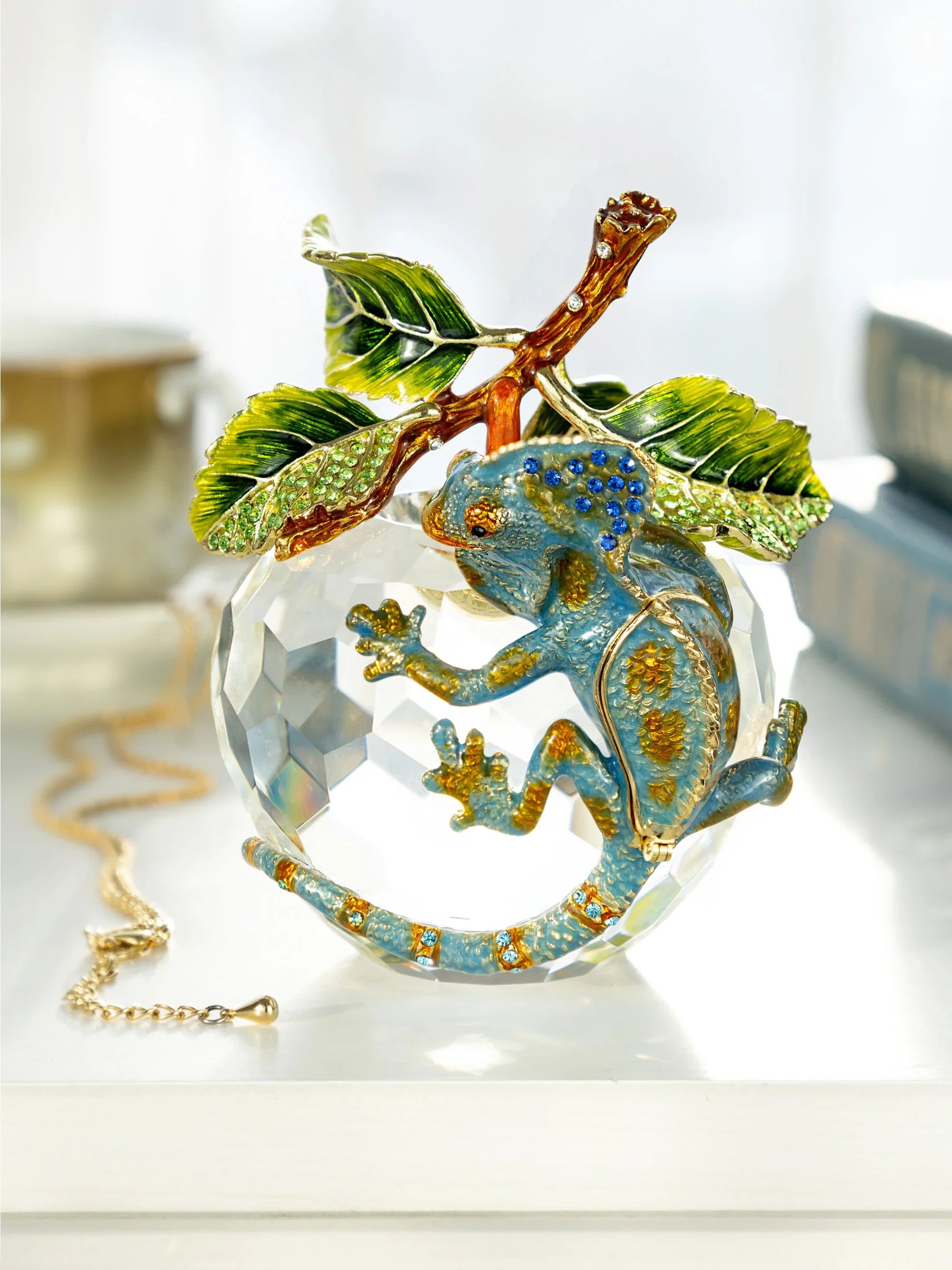 Decorative Chameleon on a branch with crystal ball, on a white surface.
