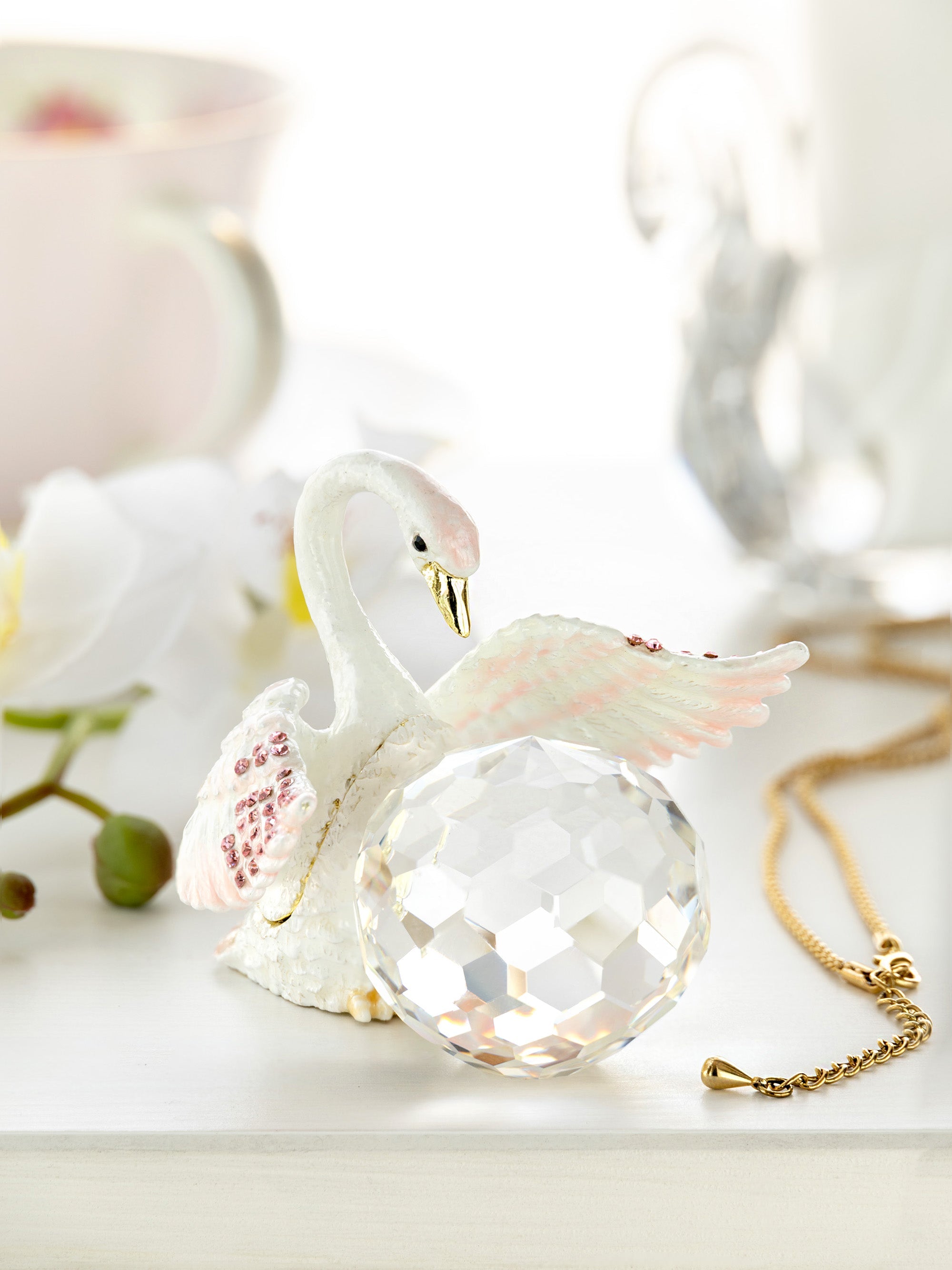 Decorative swan figurine with a crystal ball on a light background