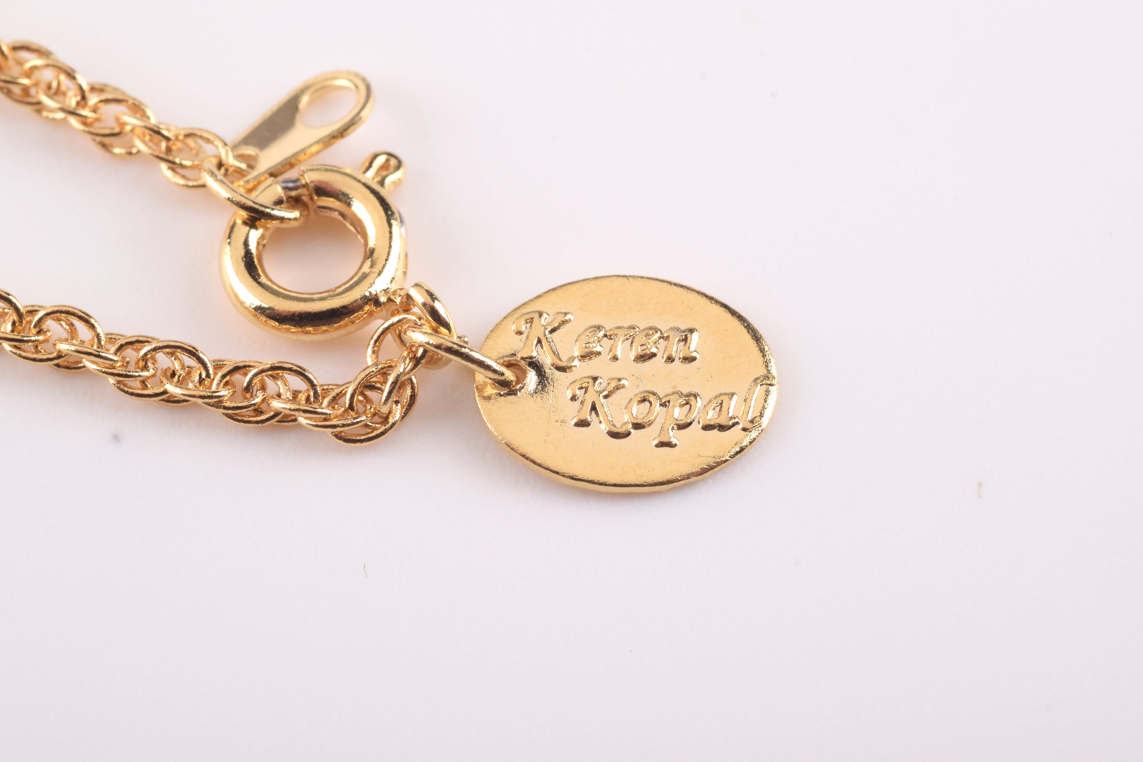 White heart-shaped pendant necklace with floral design on gold chain on white background