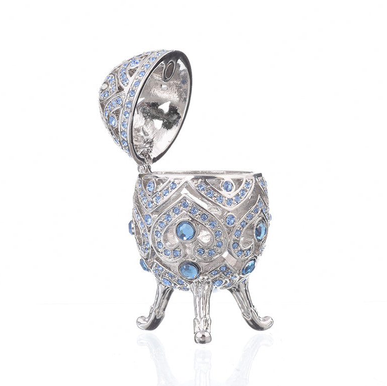 Decorative silver egg with blue gemstones on a white background