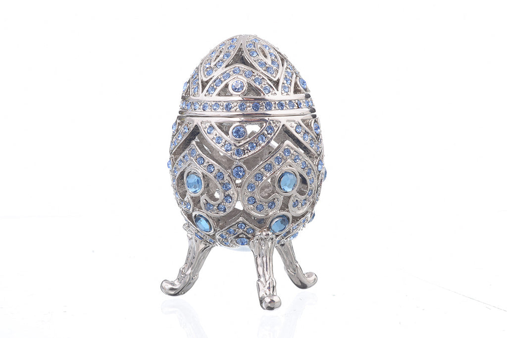 Decorative egg with blue gemstones on a white background
