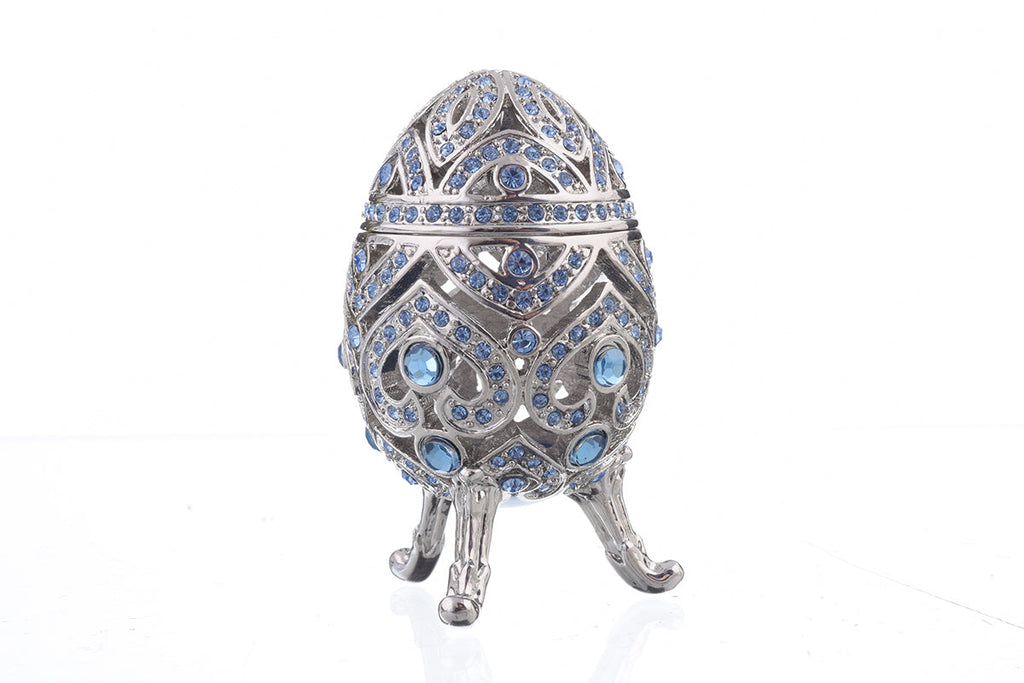Decorative egg with intricate design and blue stones on a white background