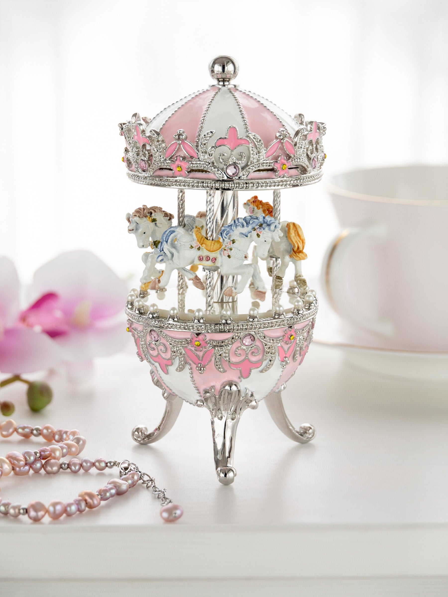 Decorative carousel figurine with pink and silver accents on a white surface.