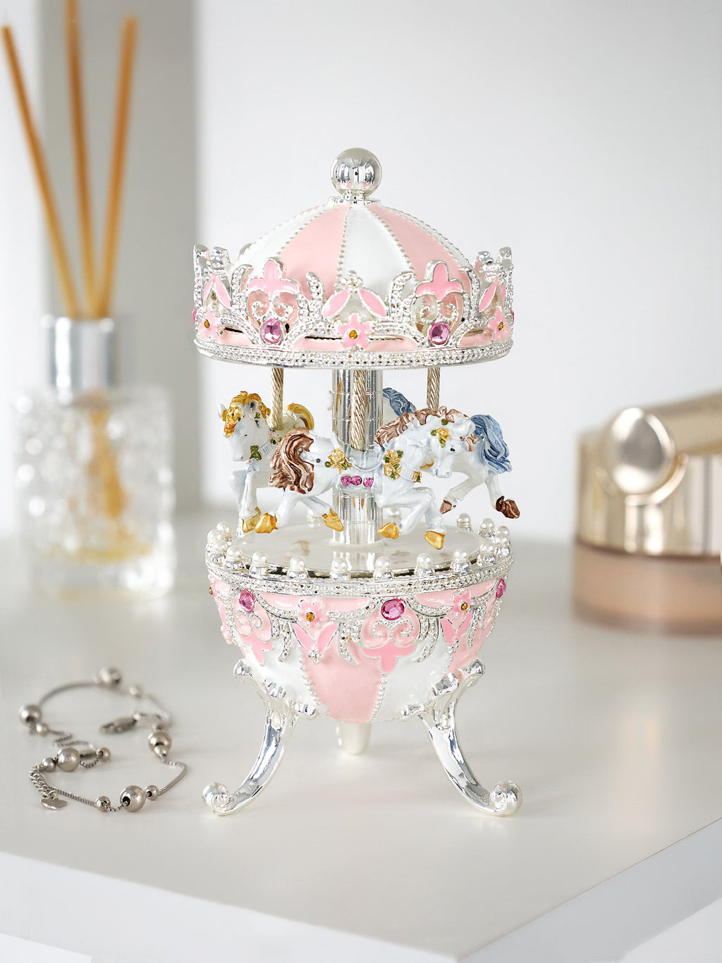 Small carousel figurine with pink top and clear base on a white surface.