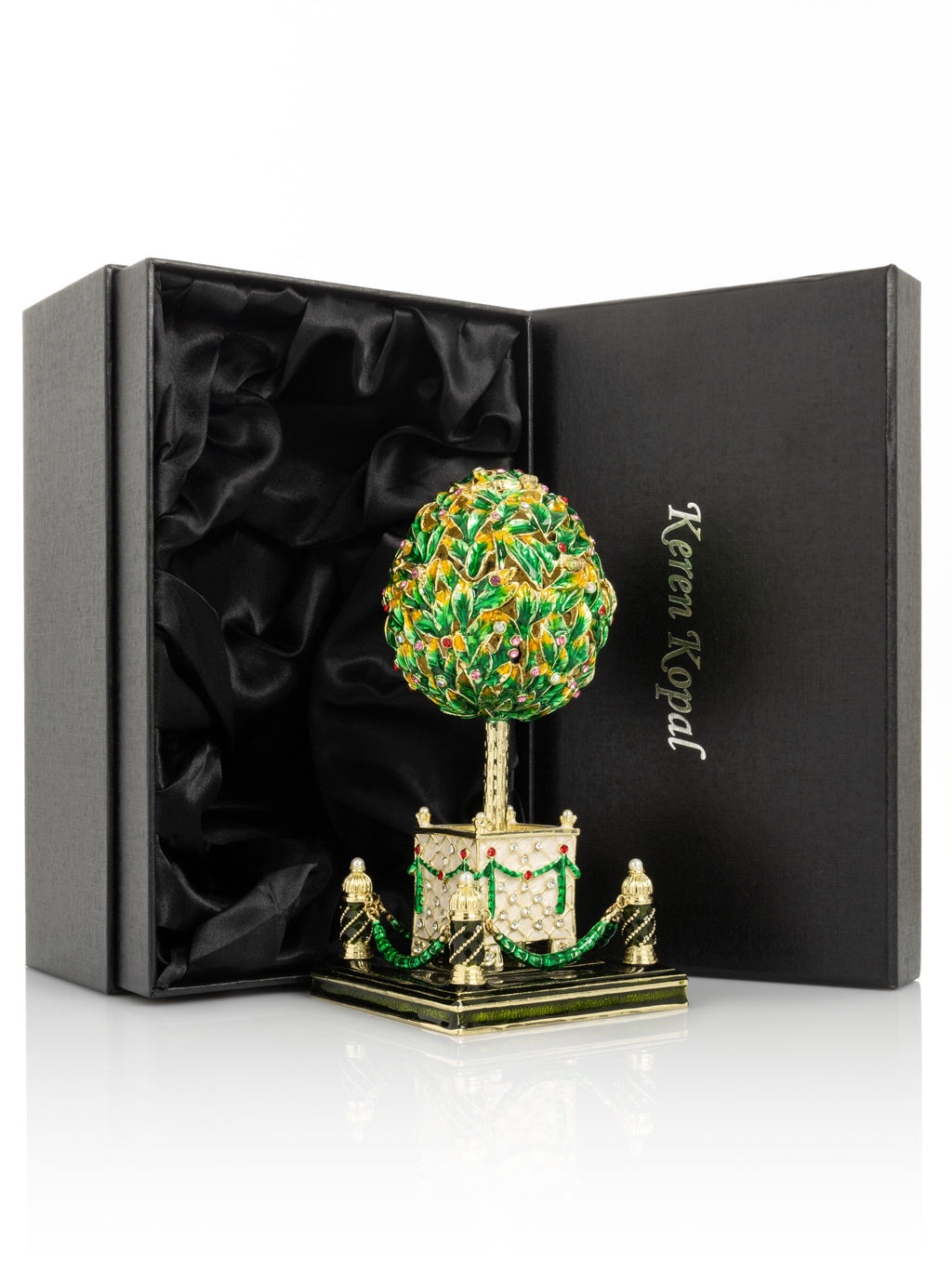 Decorative topiary sculpture with green and gold details in a black box with 'Keren Kopal' branding.