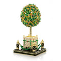 Decorative topiary sculpture with green leaves, gold accents, and a black base on a white background