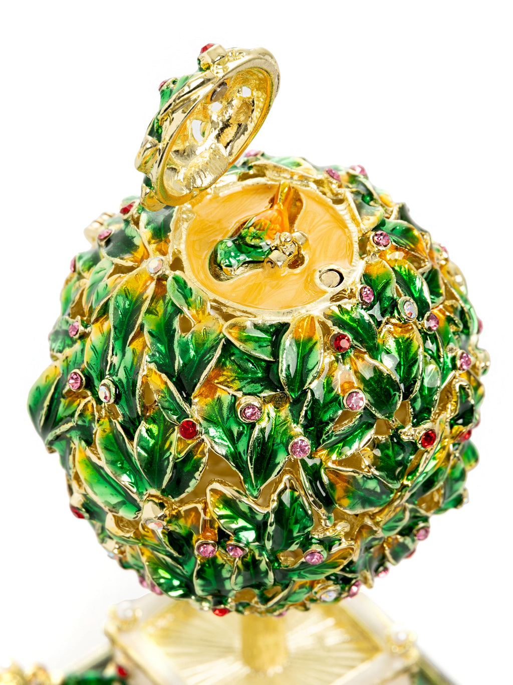 Decorative pineapple-shaped object with green leaves and gold accents on a white background