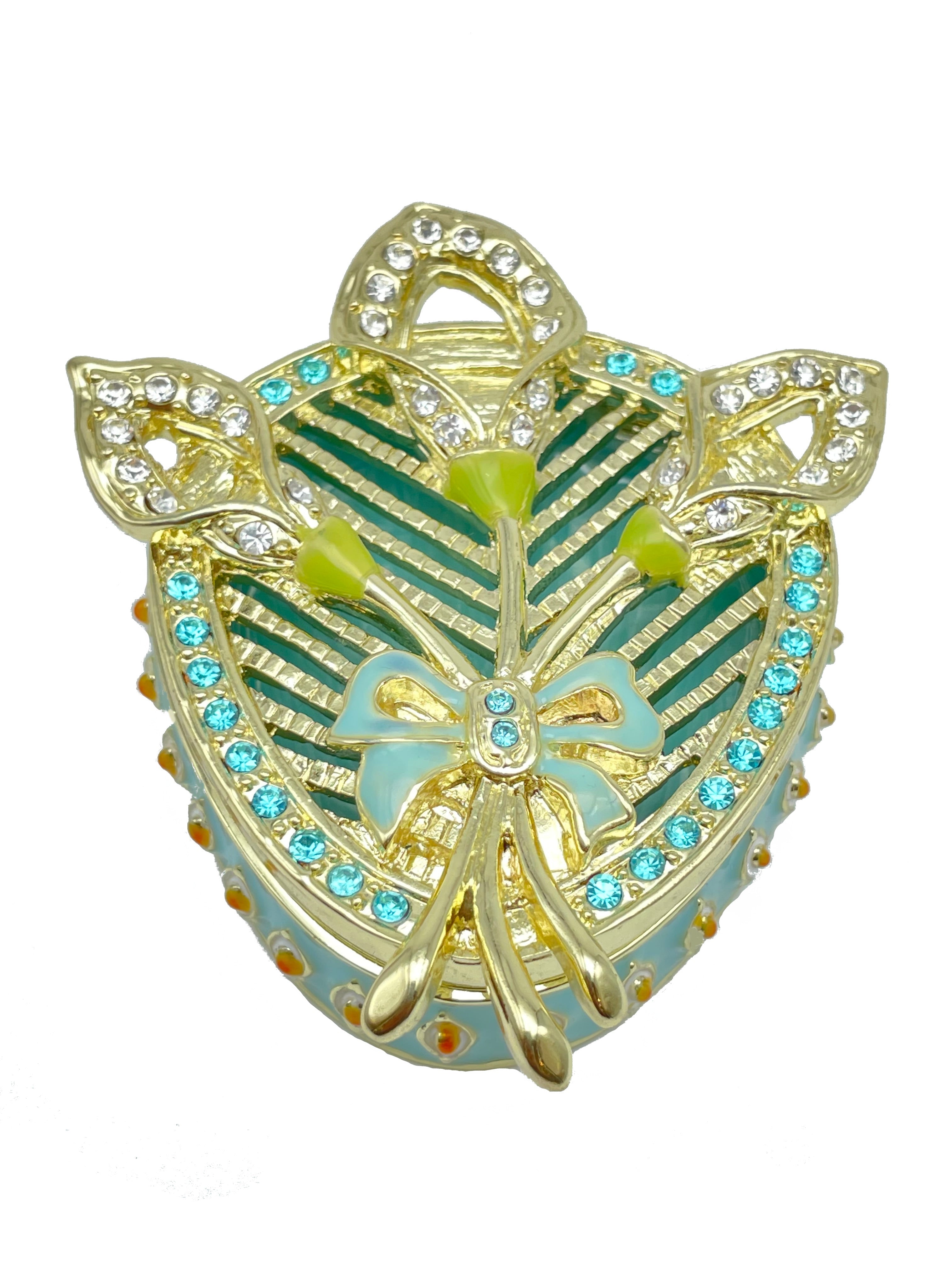 Decorative heart-shaped object with gold, green, and blue colors on a white background