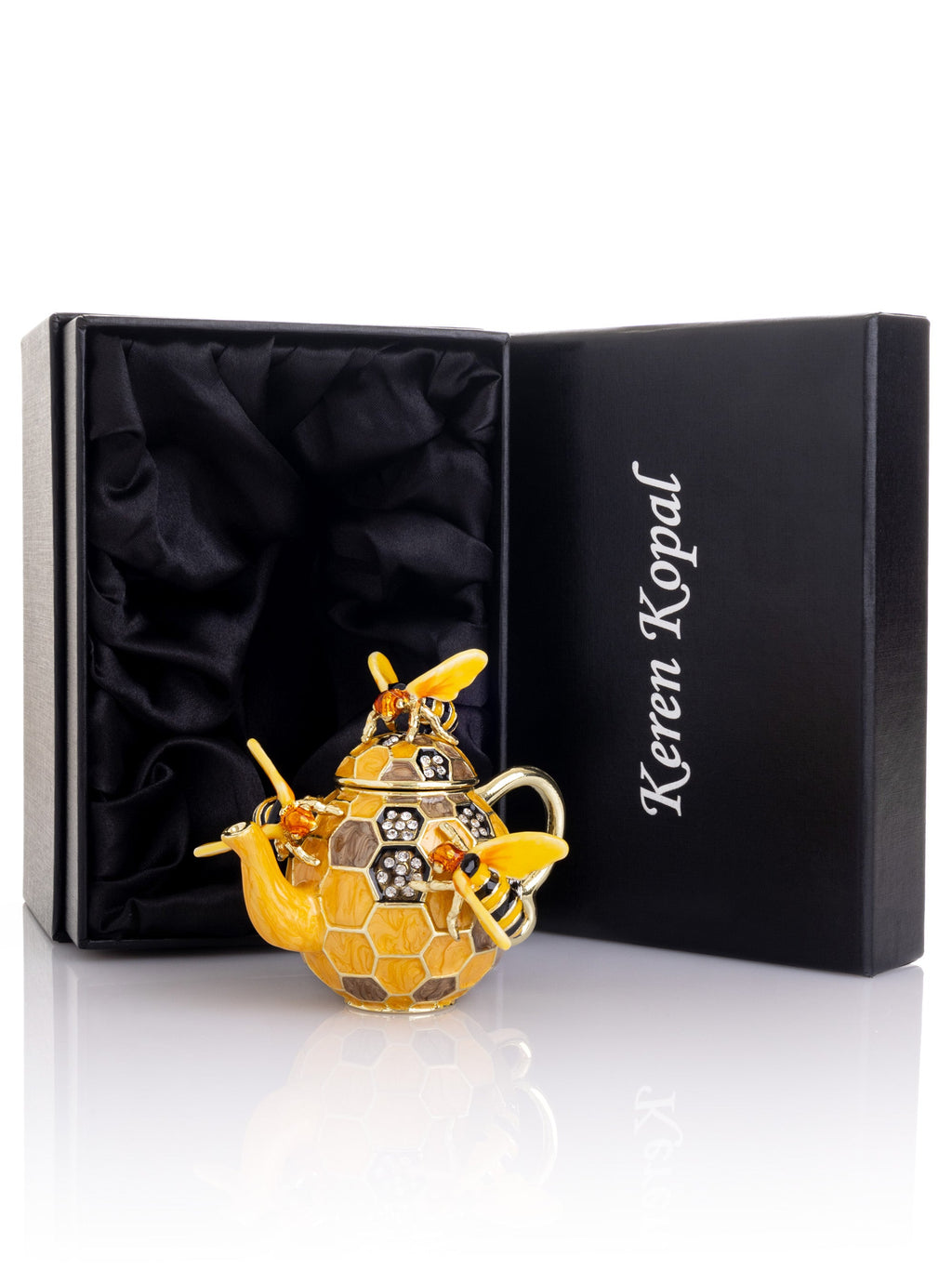 Gold teapot-shaped perfume bottle with bee design in a Keren Kopal box on a white background