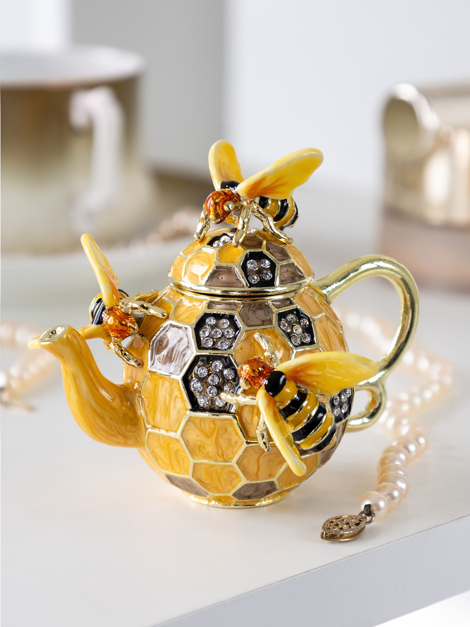 Decorative teapot with bee design on a white surface