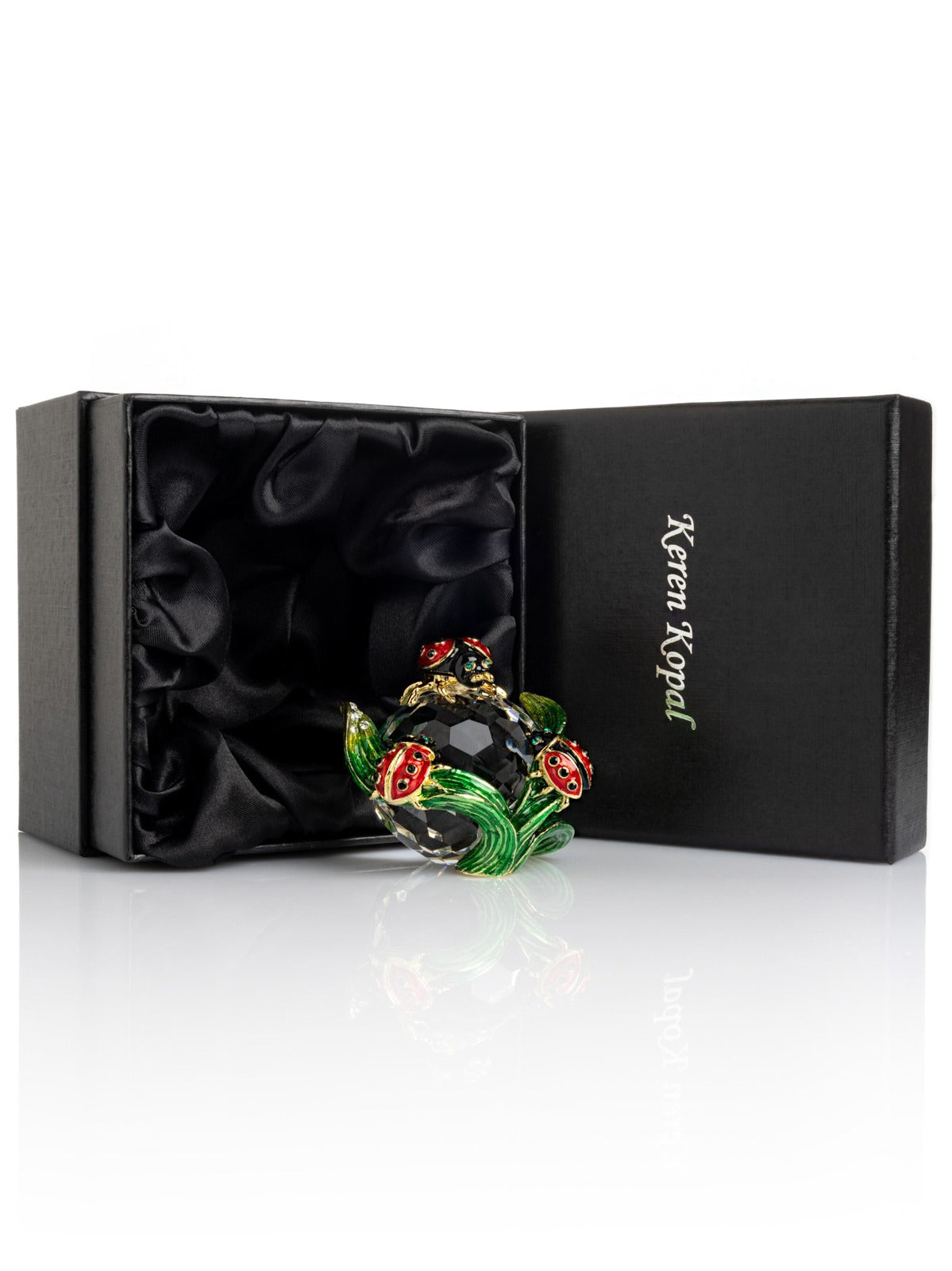 Decorative brooch with floral design in a black box labeled 'Keren Kopal'.